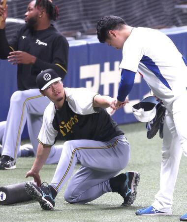 　練習中に清水とグータッチを交わす佐藤輝（左）＝撮影・北村雅宏