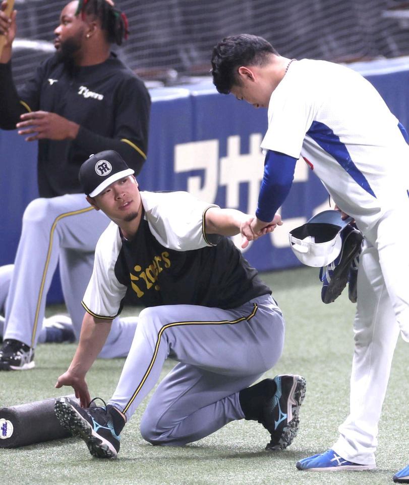 　練習中に清水とグータッチを交わす佐藤輝（左）＝撮影・北村雅宏