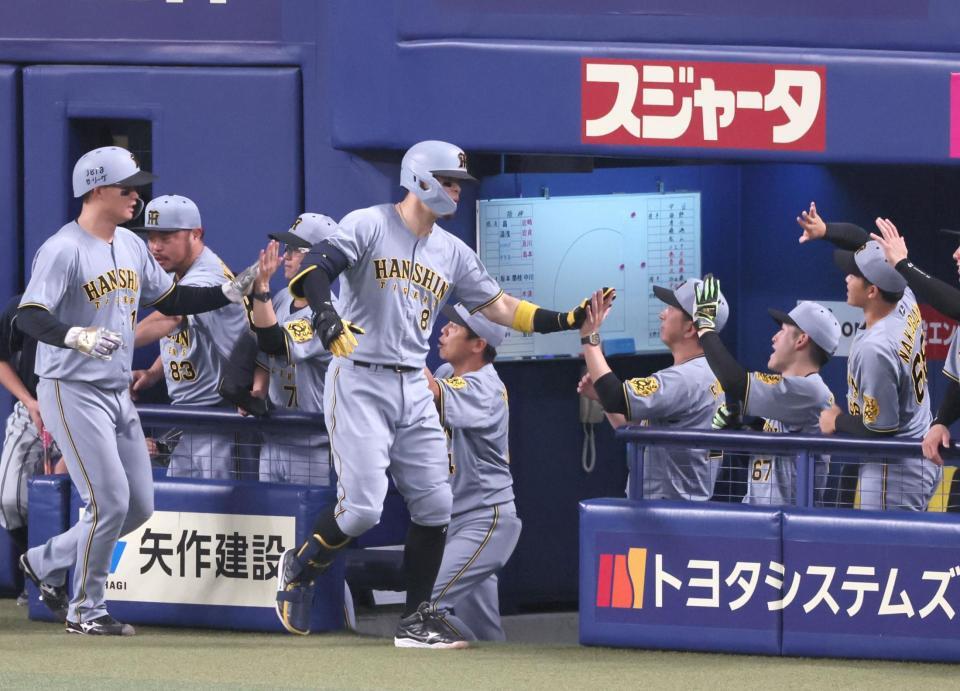 　１回、先制２ランを放ち、藤川監督（中央右）とタッチを交わす佐藤輝（撮影・立川洋一郎）