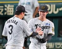 　９回表を締めくくり、大山（左）からウイニングボールを渡されて笑顔を見せる石黒＝５日