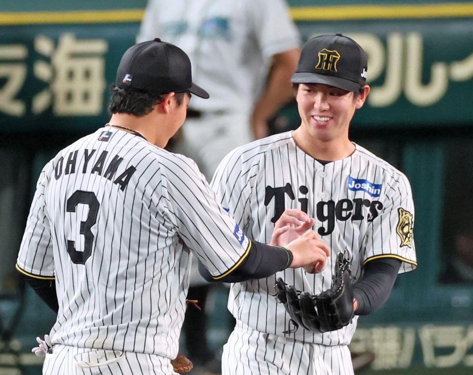 　９回表を締めくくり、大山（左）からウイニングボールを渡されて笑顔を見せる石黒＝５日