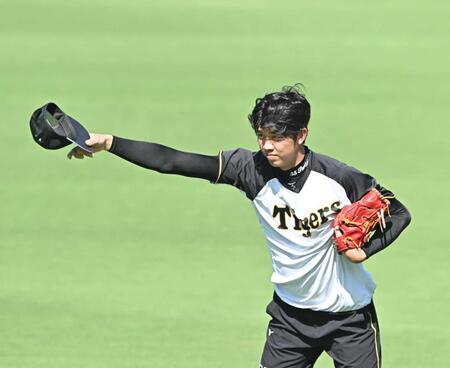 　キャッチボールで暴投し帽子を取る才木