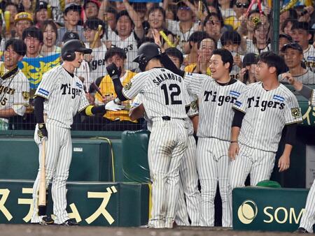 　６回、ベンチ前で中犠飛を放った近本（左）とタッチを交わす生還した三走坂本