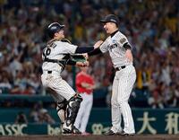 　リーグ優勝を決め、抱き合う阪神の岩崎（右）と坂本のバッテリー