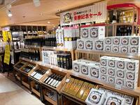 阪　神百貨店の和洋酒コーナーに記念ロゴ入りの様々な種類の酒が並ぶ