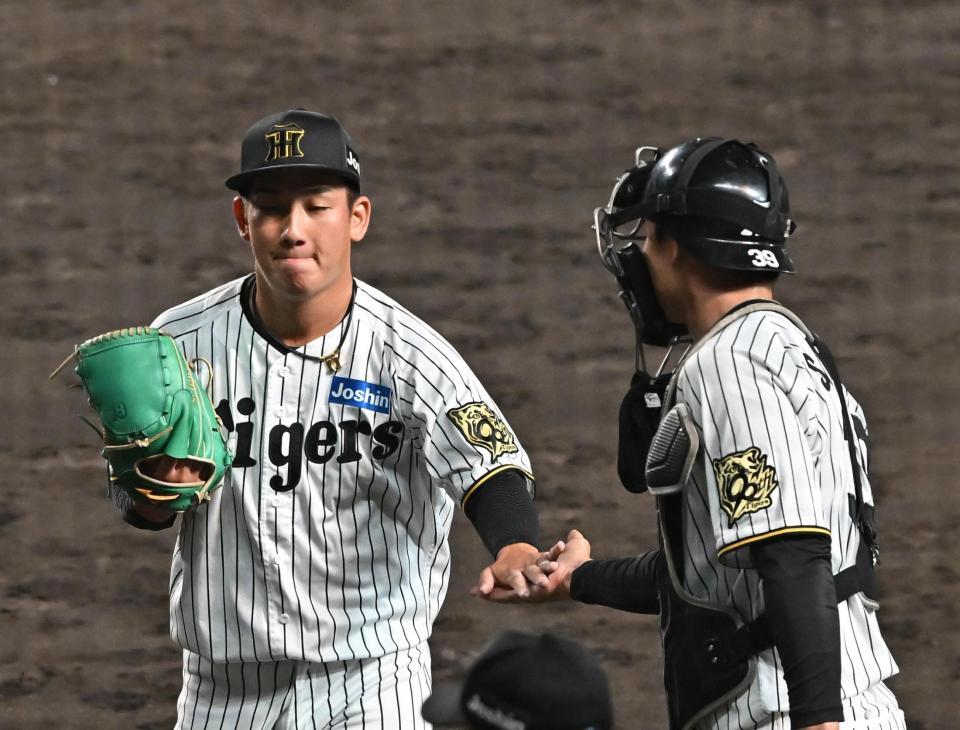 　９回を無失点に抑え、栄枝（右）とタッチを交わす伊原（撮影・西田忠信）