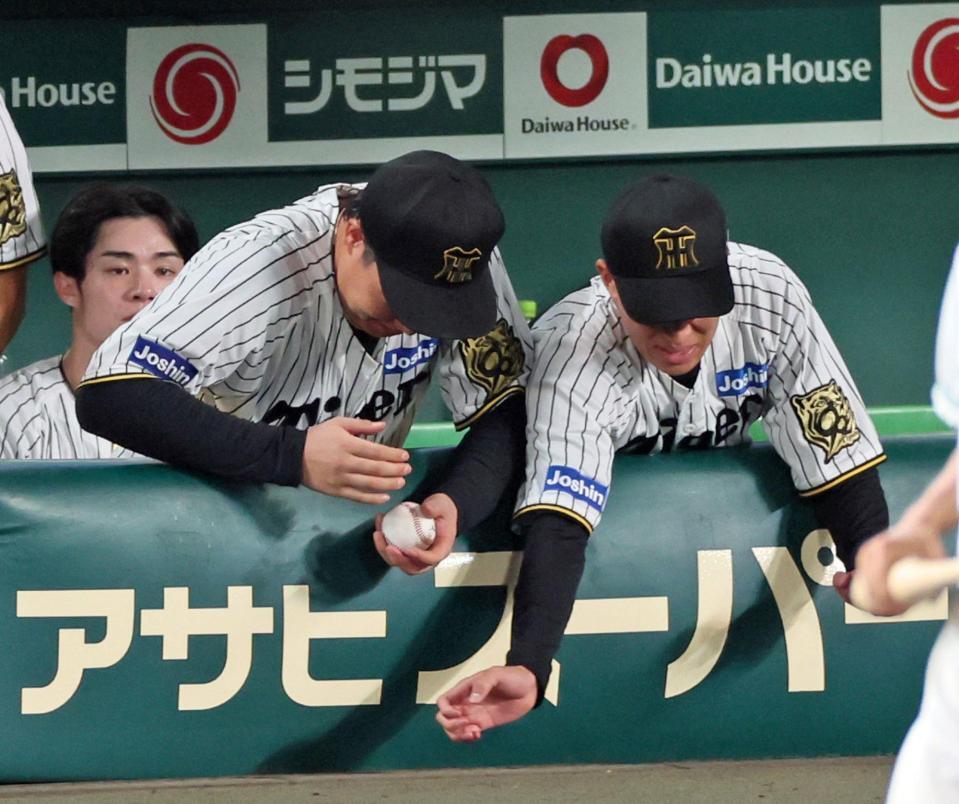 　９回、楠本が阪神での初ヒットを放ち記念ボールを手に取る大山＝１０日