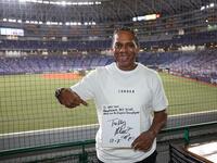 　佐藤輝へのメッセージを色紙に書き込み、笑顔のローズ氏（撮影・坂部計介）