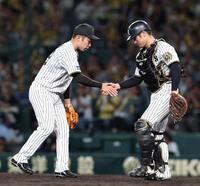 　９回、最後を締めた石井は坂本（右）と握手を交わす（撮影・北村雅宏）
