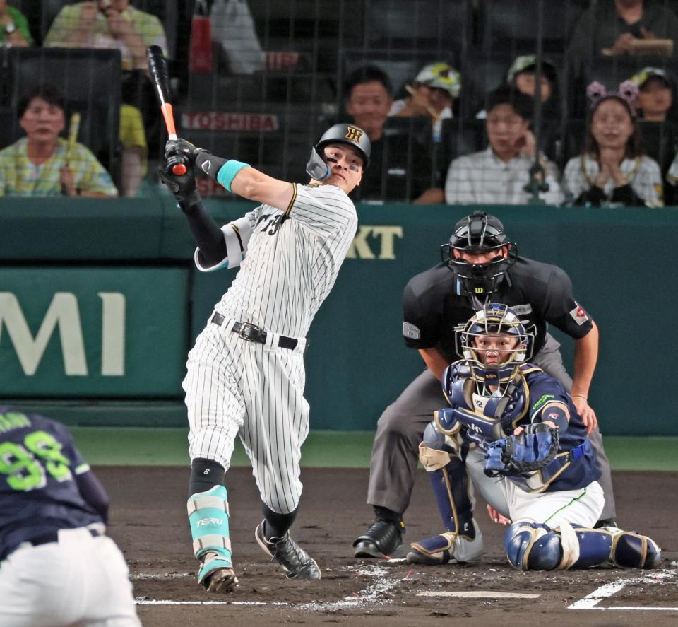 　１回、先制の左犠飛を放つ佐藤輝（撮影・立川洋一郎）