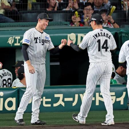 　８回を無失点で切り抜け、リリーフした岩貞（１４）とタッチを交わす湯浅（撮影・立川洋一郎）