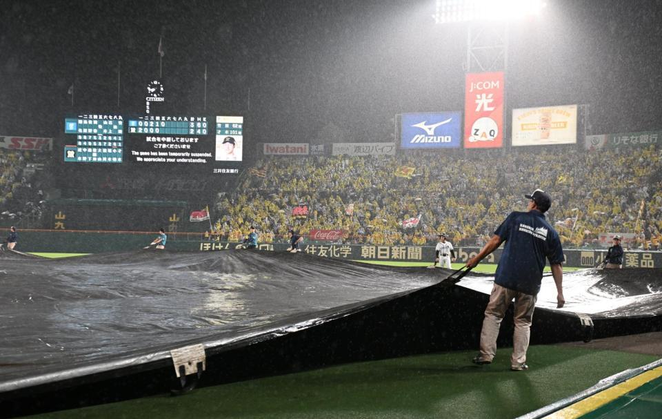 　雨で中断し、シートが掛けられるグラウンド