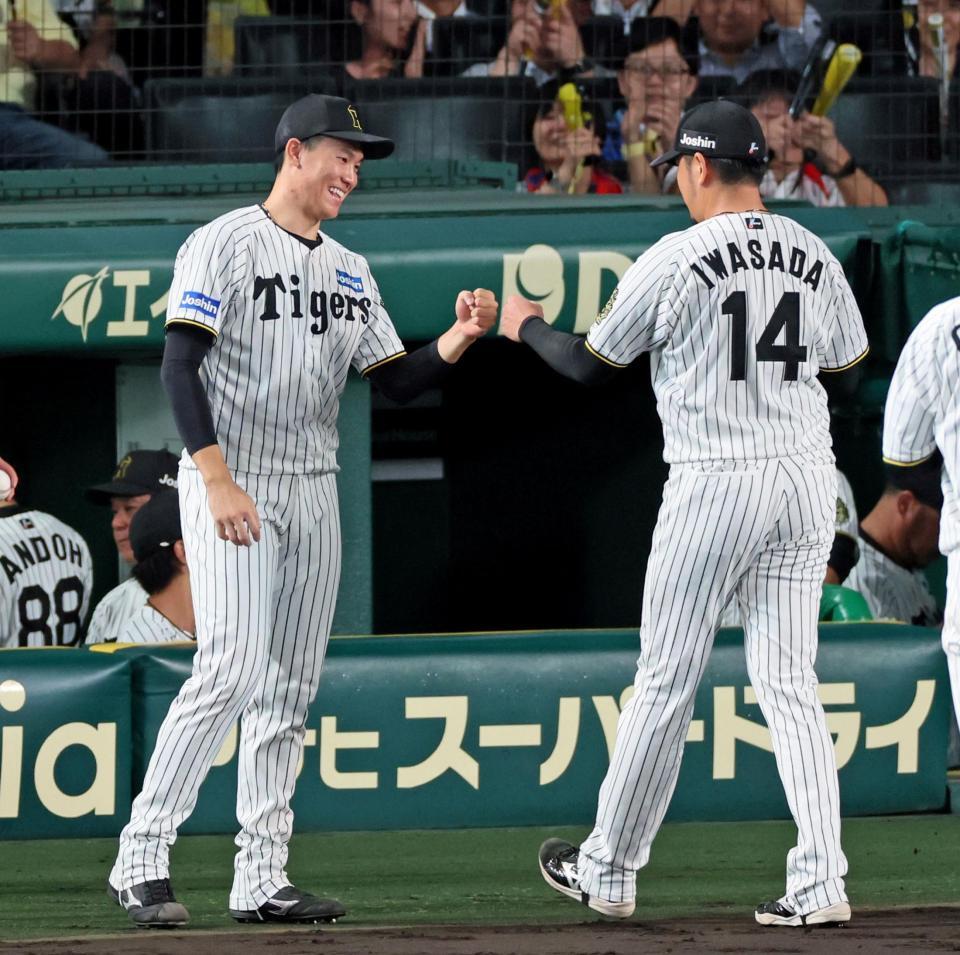 　８回を無失点で切り抜け、リリーフした岩貞（１４）とタッチを交わす湯浅（撮影・立川洋一郎）