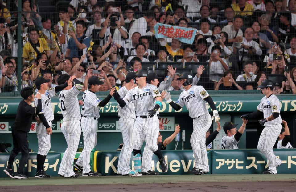 　１回、先制３ランを放ちベンチで迎えられる佐藤輝