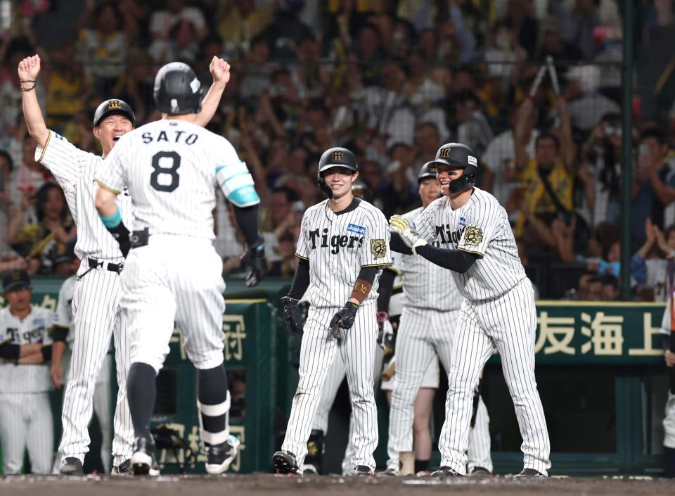 　１回、先制３ランを放った佐藤輝（８）を笑顔で迎える（右から）森下、中野（撮影・北村雅宏）