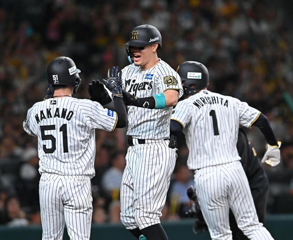 　１回、先制３ランを放ち、中野（５１）と森下（１）に迎えられる佐藤輝（撮影・西田忠信）