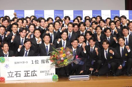 　阪神から１位指名を受け、笑顔でガッツポーズする創価大・立石正広（中央）＝撮影・西岡正