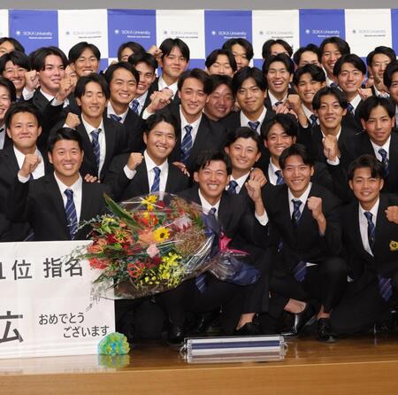 　阪神から１位指名を受け、笑顔でガッツポーズする創価大・立石正広（中央）＝撮影・西岡正