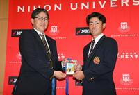 　ドラフト２位指名され、吉野誠スカウト（左）から藤川球児監督のサイン入りパスを受け取る日大・谷端将伍（撮影・伊藤笙子）