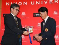 　ドラフト２位指名され、吉野誠スカウト（左）から藤川球児監督のサイン入りパスを受け取る日大・谷端将伍（撮影・伊藤笙子）