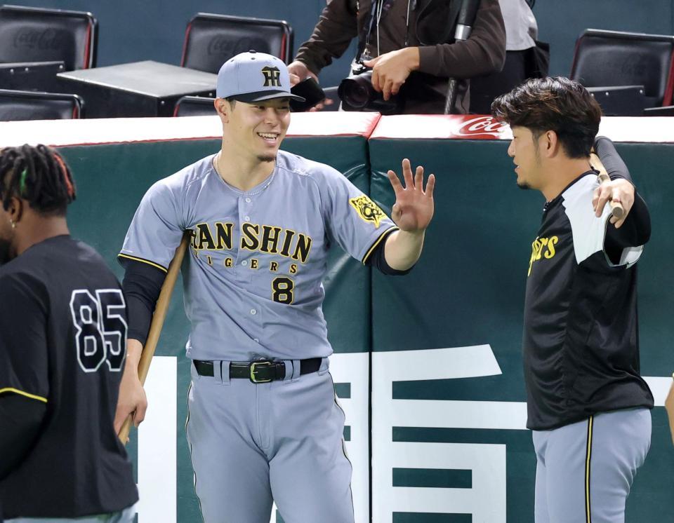 　岩貞（右）とウオーミングアップをしながら談笑する佐藤輝（撮影・立川洋一郎）