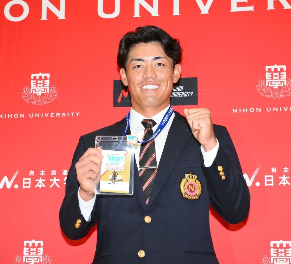 　ドラフト２位指名され、藤川球児監督のサイン入りパスを手に笑顔を見せる日大・谷端将伍（撮影・伊藤笙子）