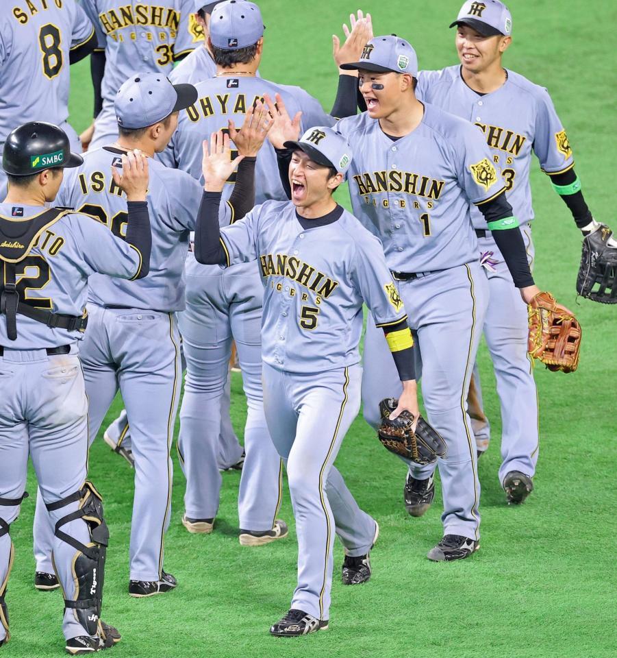 　接戦で日本シリーズ初戦を勝利し雄たけびを上げタッチを交わす近本（５）ら阪神ナイン（撮影・立川洋一郎）