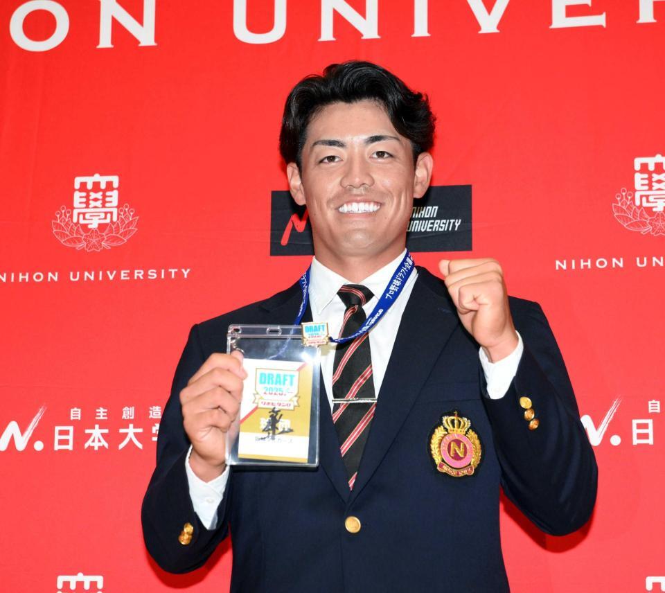 　藤川監督のサインが入ったドラフト会場のパスを手に笑顔を見せる日大・谷端（撮影・伊藤笙子）