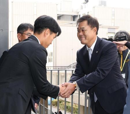 　平塚克洋スカウト（右）と握手をするドラフト３位指名の筑波大・岡城快生（撮影・佐々木彰尚）