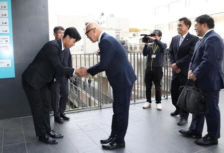 　畑山俊二統括スカウト（右）と握手をする３位指名の筑波大・岡城快生（撮影・佐々木彰尚）