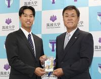 　平塚克洋スカウト（右）から藤川監督のサイン入りドラフト会議パスを受け取るドラフト３位指名の筑波大・岡城快生（撮影・佐々木彰尚）