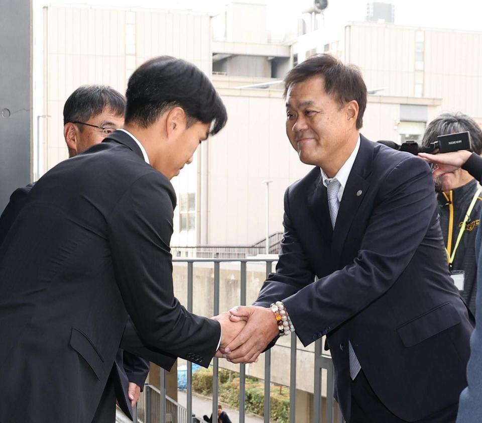 　平塚克洋スカウト（右）と握手をするドラフト３位指名の筑波大・岡城快生（撮影・佐々木彰尚）