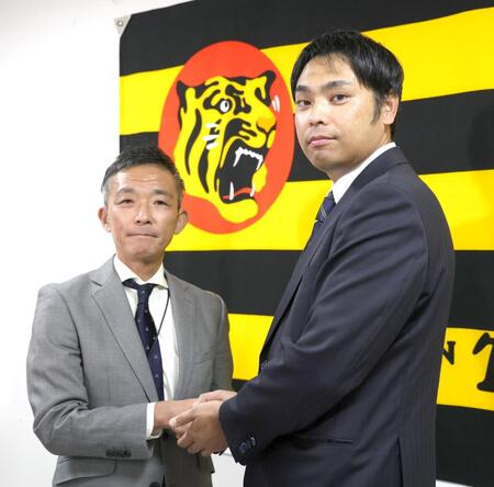 　竹内孝行球団副本部長（左）と握手を交わす桑原謙太朗新投手コーチ（撮影・北村雅宏）