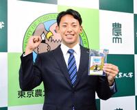 　藤川監督のサイン入りＩＤを手に笑顔を見せる東農大北海道オホーツク・神宮（撮影・間宮涼）