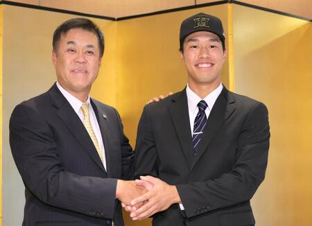 　仮契約交渉を終え、平塚担当スカウト（左）と握手するドラフト３位指名の岡城快生（撮影・吉澤敬太）