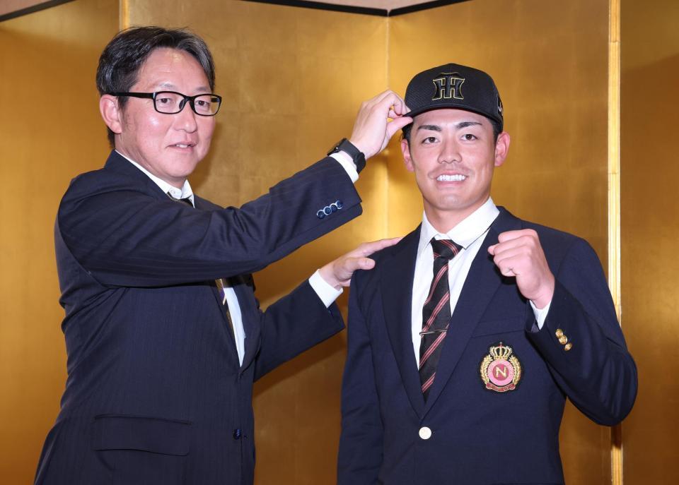 　仮契約を終え吉野担当スカウトに帽子をかぶらせてもらい笑顔のドラフト２位指名の日大・谷端将伍（撮影・金田祐二）