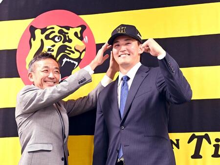 　竹内球団副本部長（左）から帽子をかぶらせてもらい笑顔の元山（撮影・飯室逸平）