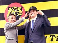 　竹内球団副本部長（左）から帽子をかぶらせてもらい笑顔の元山（撮影・飯室逸平）