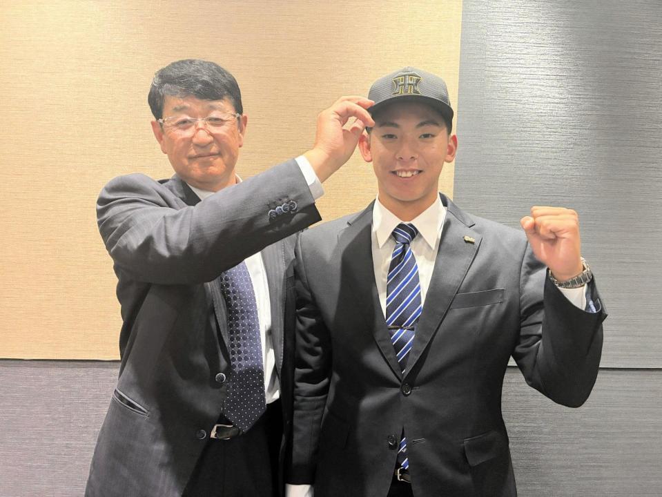 　葛西担当スカウト（左）に帽子をかぶせられる神宮（右）＝球団提供