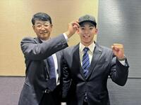 　葛西担当スカウト（左）に帽子をかぶせられる神宮（右）（球団提供）