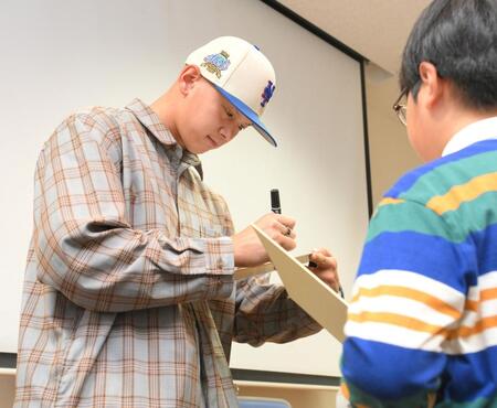 　オイシックス新潟「ドラフト指名を祝う会」でファンにサインを書く阪神ドラフト５位・能登嵩都（撮影・伊藤笙子）