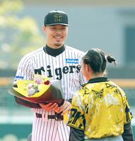 　花束を渡され笑顔を見せる佐藤輝（撮影・立川洋一郎）