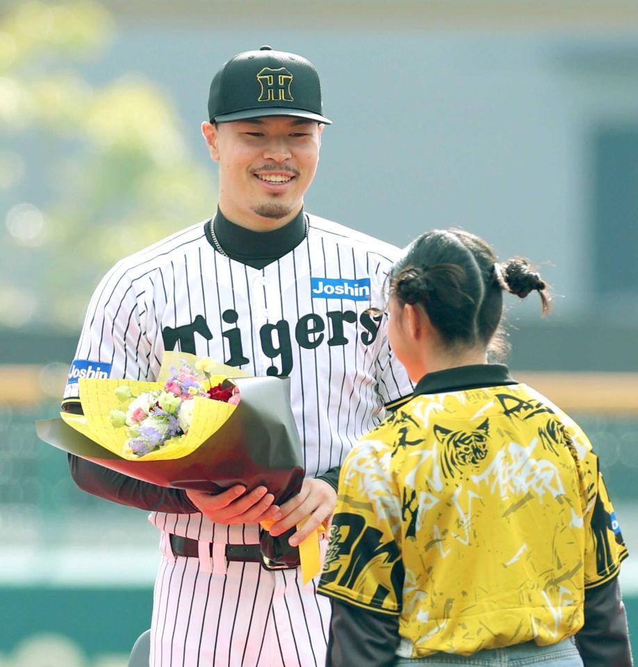 　花束を渡され笑顔を見せる佐藤輝（撮影・立川洋一郎）