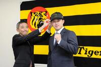 　阪神・竹内孝行球団副本部長（左）から帽子を被せてもらう浜田（撮影・山口登）