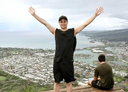 　頂上にたどり着き、ホノルル市街を背に両手を上げる大竹（撮影・田中太一）