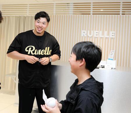 　ＲＵＥＬＬＥ大阪堀江店で１日店長を務める佐藤輝（左）、来店者にサインする（撮影・山口登）