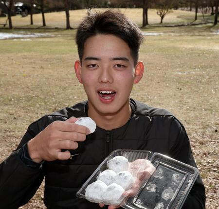 　地元産の黒豆大福をほおばる早瀬（撮影・田中太一）