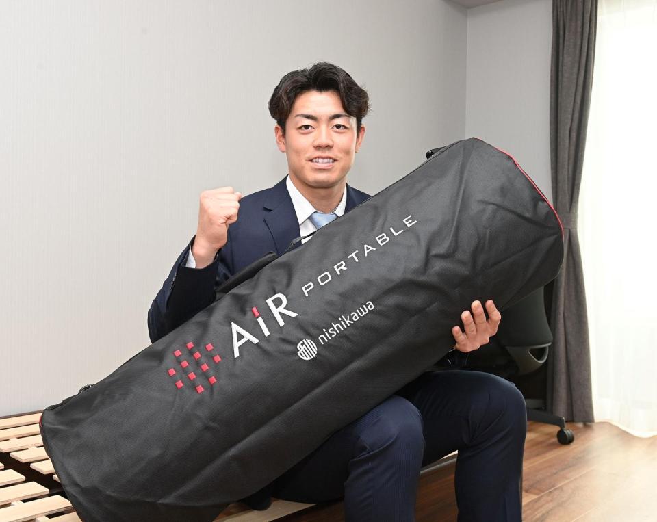 　持参したマットレスを手にガッツポーズするドラフト２位の谷端（撮影・西田忠信）