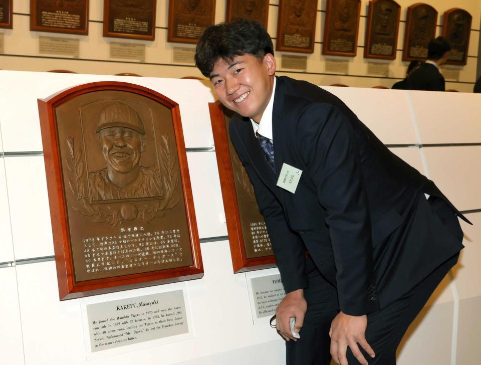 　掛布雅之氏のレリーフの前で笑顔を見せる立石（撮影・伊藤笙子）