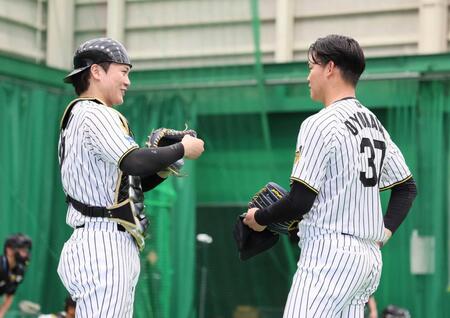 　ブルペンでの投球を終えて話し合う伏見（左）と及川